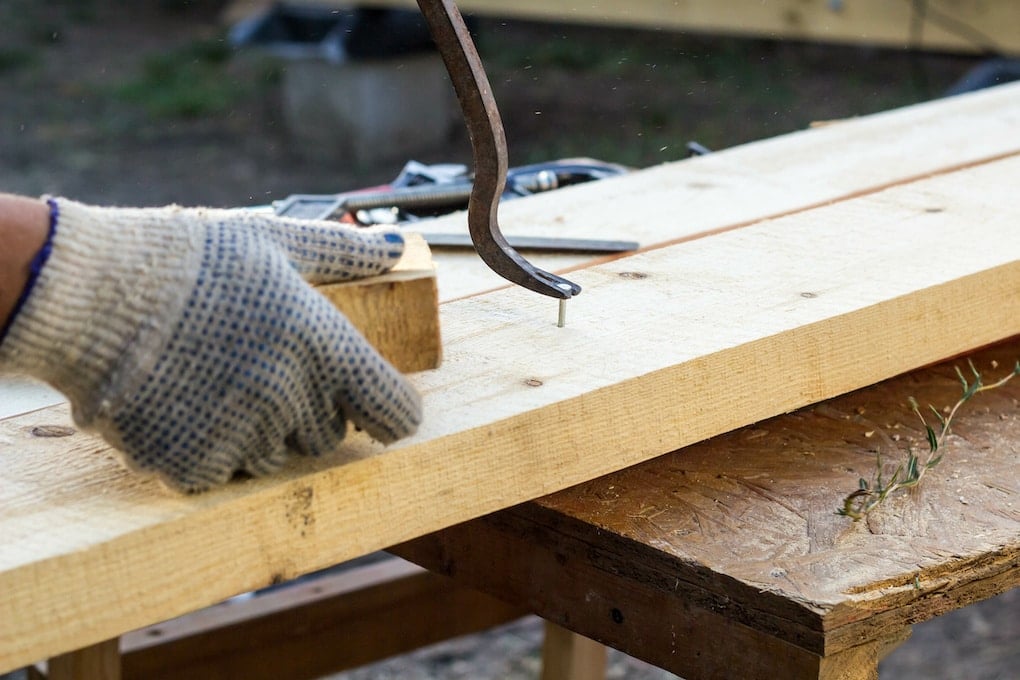 carpenter pulling a nail from reclaimed barnwood