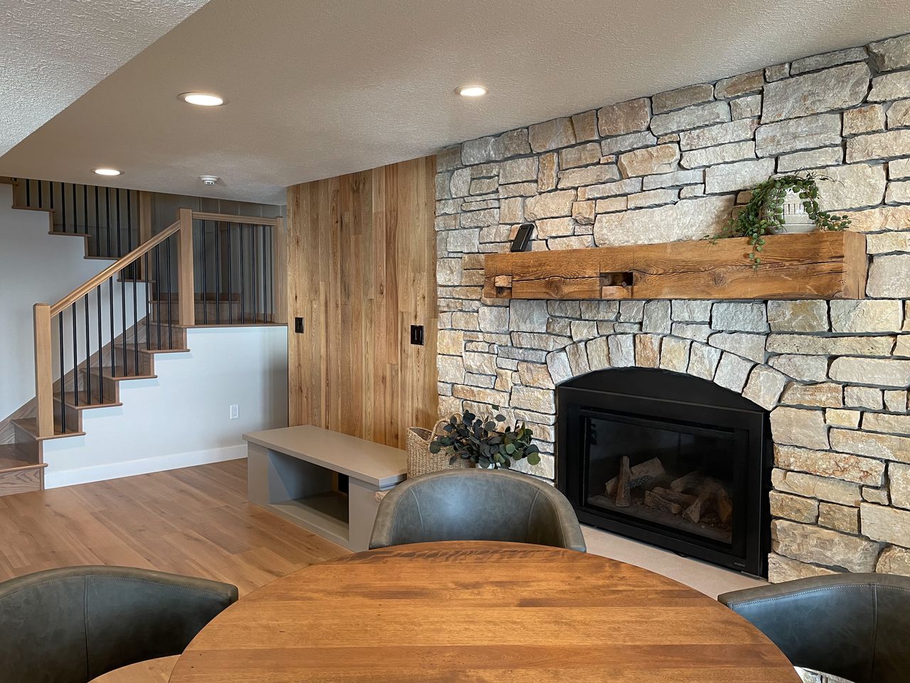 living room in the basement with a fireplace, reclaimed wood mantel, and an accent wall with a little bench area