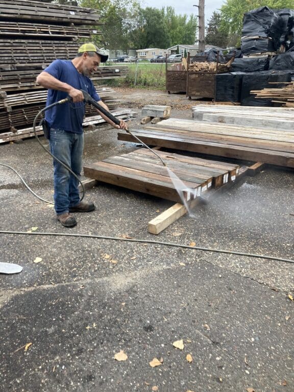 Manomin resawn timbers employee powerwashing reclaimed wood