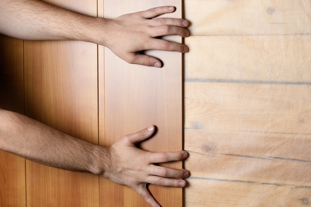 pair of hands installing wood panel; reclaimed wood wall ideas