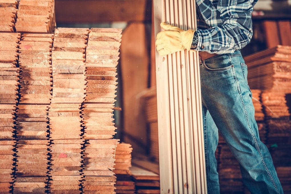 man carrying stack of wood at lumber yard; reclaimed wood wall ideas