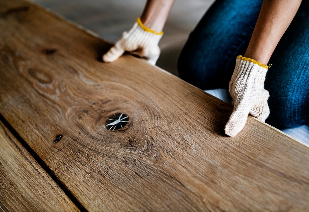 person kneeling showing how to install reclaimed wood flooring