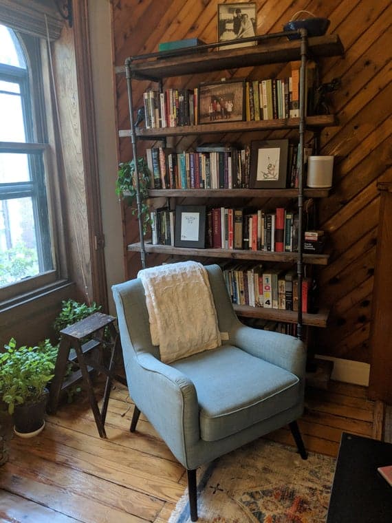 blue arm chair in front of reclaimed wood bookcase