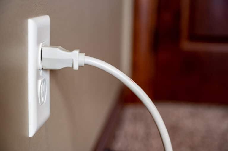 Side view of white power cord plugged into a white wall outlet; diy planked walls