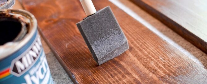 hand using brush to apply one of the best wood stain options