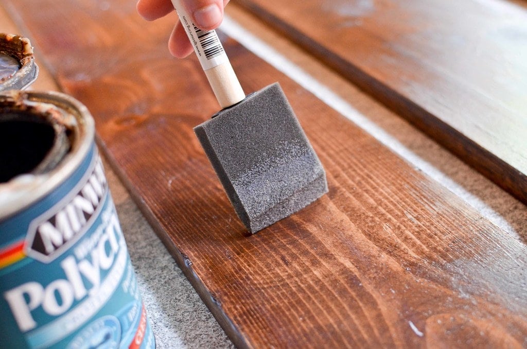 hand using brush to apply one of the best wood stain options