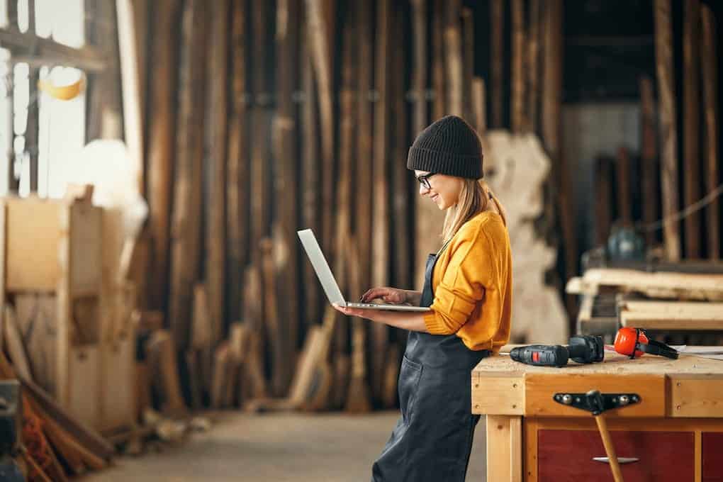young female carpenter searching reclaimed wood near me on laptop