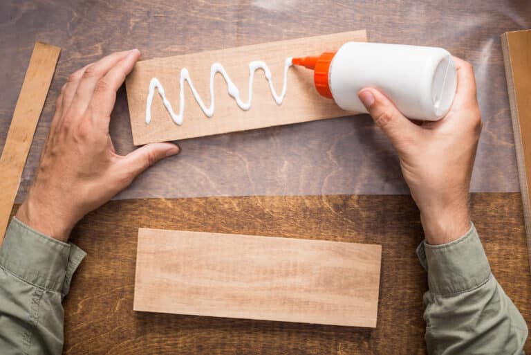 man gluing wood pieces for reclaimed wood floating shelves