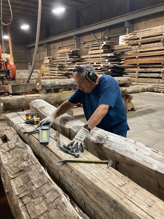 a worker at Manomin de-nailing some reclaimed wood that has just came into the shop