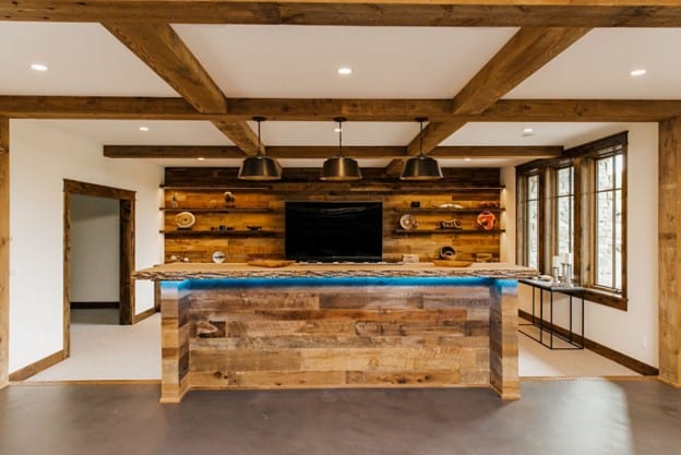 Basement home bar with reclaimed wood paneling and coffered decorative ceiling