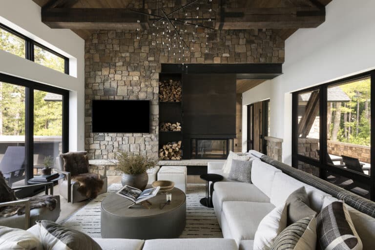Modern industrial living room with stone walls, steel features, and reclaimed timber decorative ceiling truss.