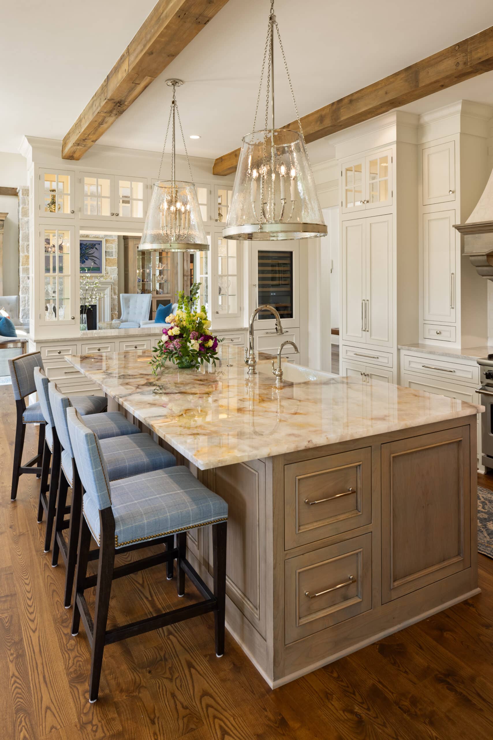 a side looking of the island with bar stool seating and sconce lighting hanging down above the island and the box beams across the ceiling