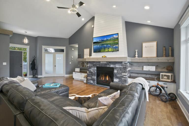 Extended reclaimed wood mantel across a modern living room with a stone faced fireplace.