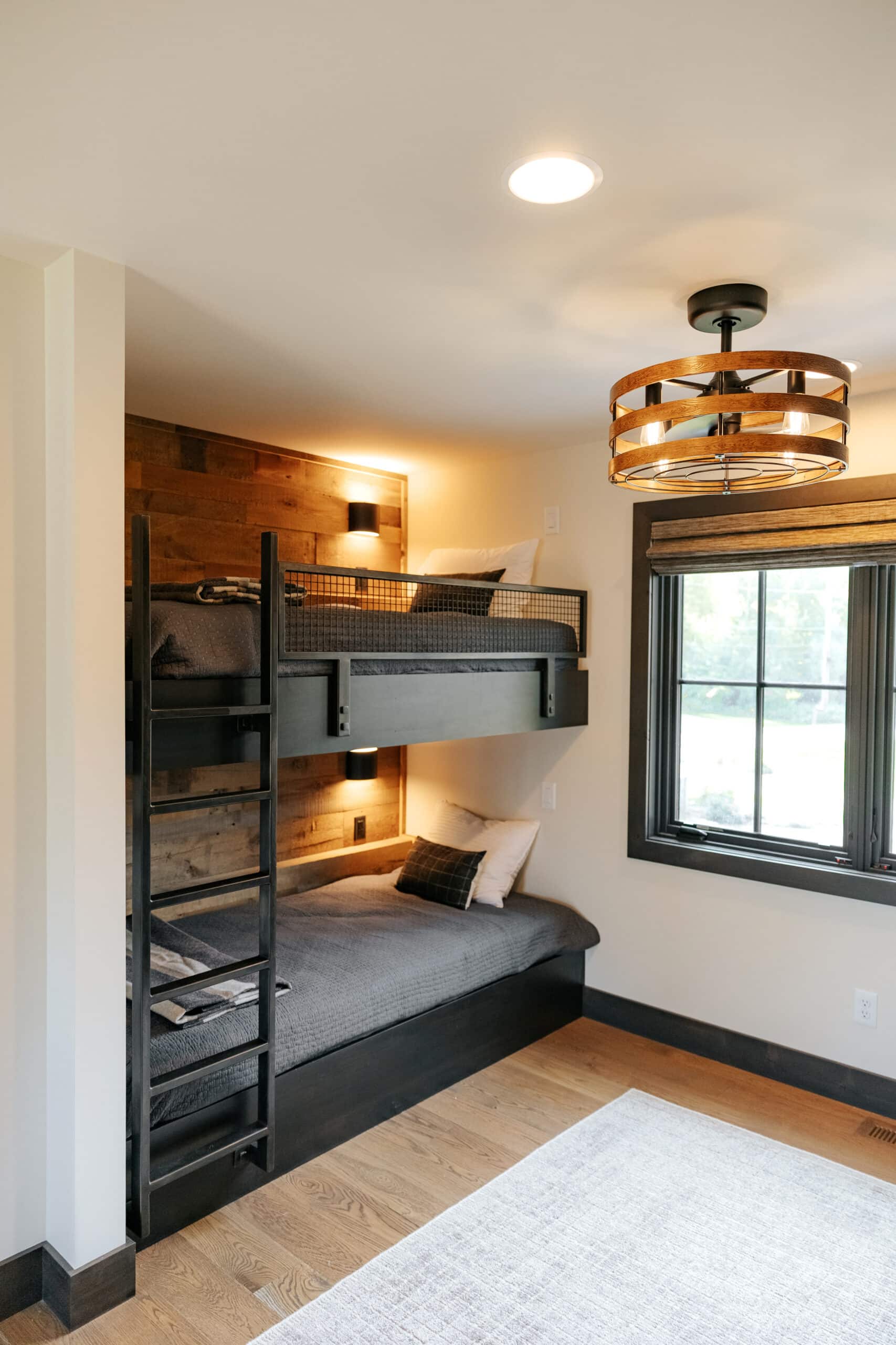 Metal modern bunk beds with reclaimed wood paneling on the walls behind them.