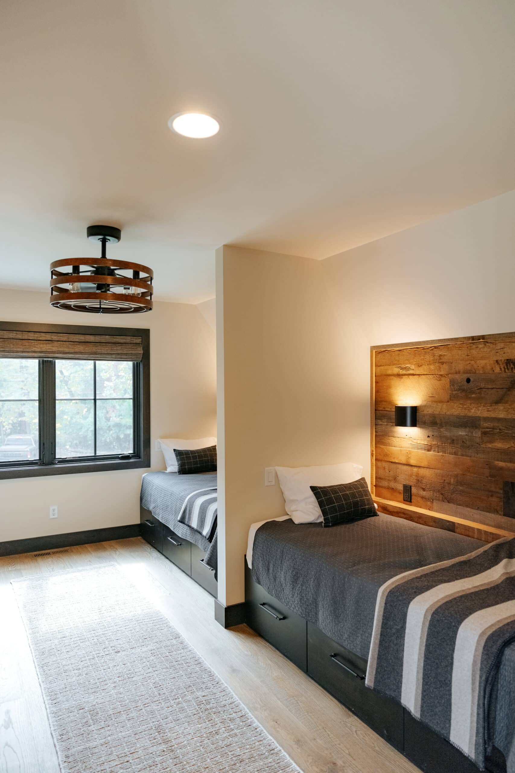 Two beds in a shared bedroom with modern design and reclaimed wood paneling on the walls behind each bed.