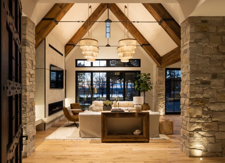 Great room of a luxury home built by Nor-Son Custom Builders. Vaulted ceilings with wooden box beams, stone faced walls and custom light fixtures.