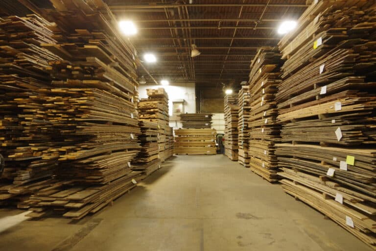 A warehouse full of stacks of reclaimed wood lumber made from sustainable old growth wood.