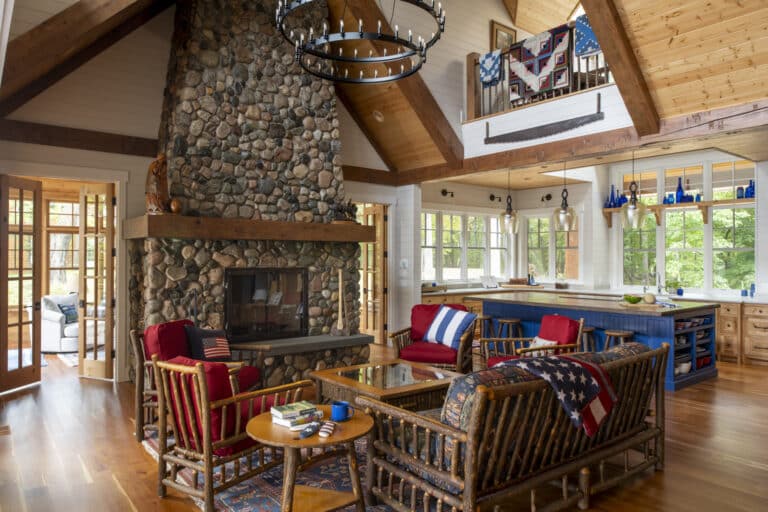 Living room of a cottage style custom home by Nor-Son Custom Builders. Room features a grand stone faced fireplace and rustic log furniture.