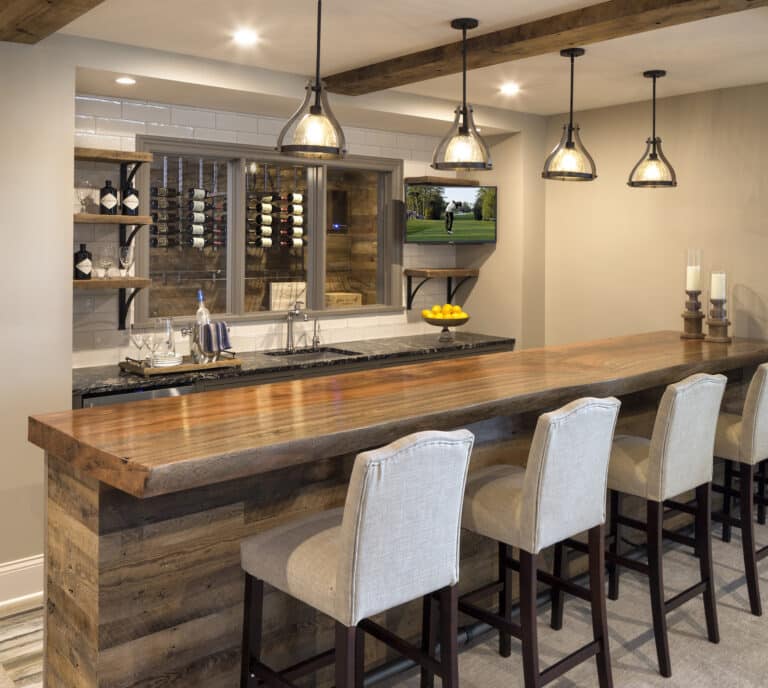 Reclaimed wood bar panels and box beams on the ceiling above. A window shows a wine cellar also built in reclaimed wood.