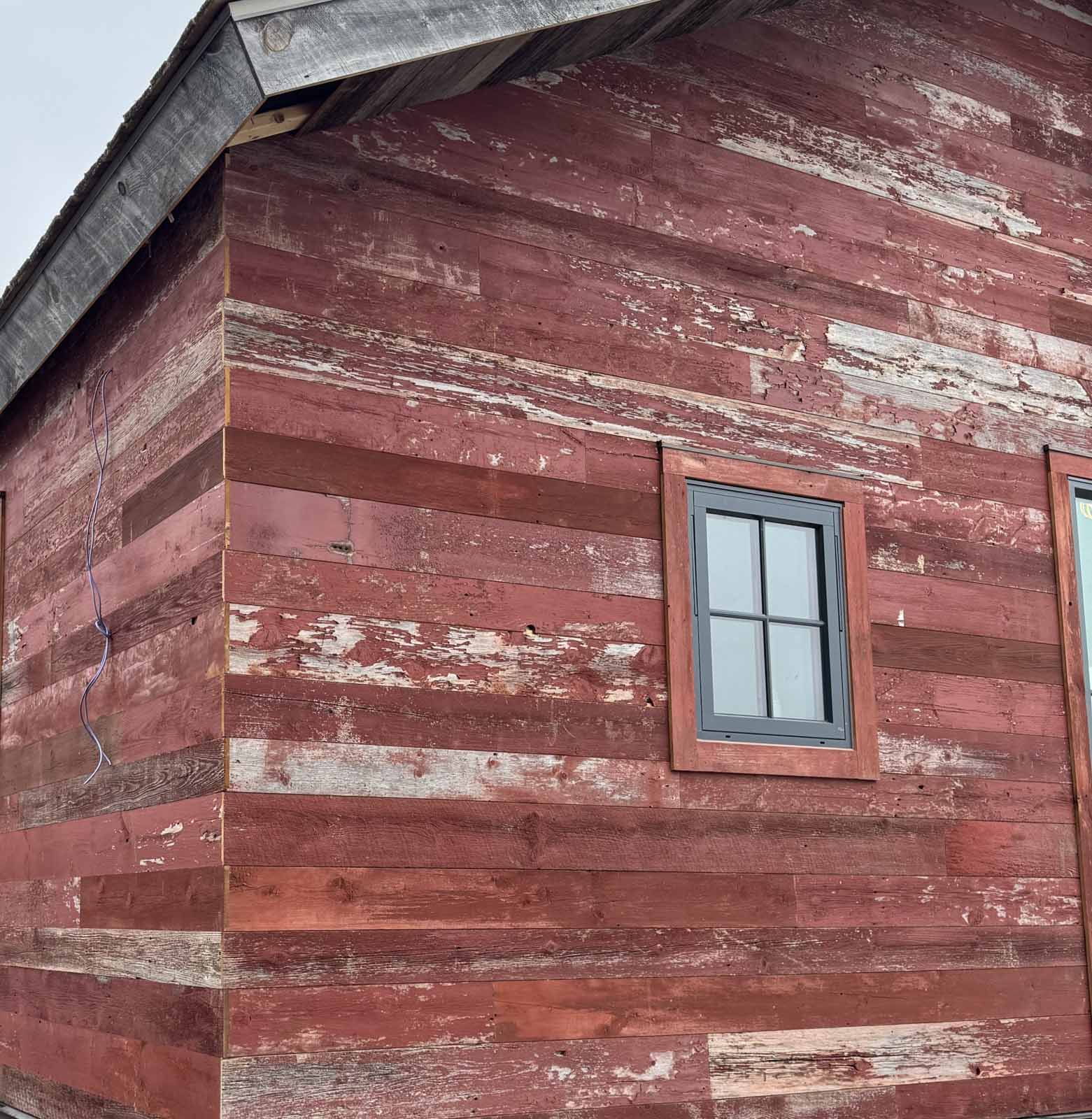 Reds-Reclaimed-Wood-Paneling-6 Reclaimed wood antique red barnwood paneling on the exterior of a lodge style home, detail of siding with window