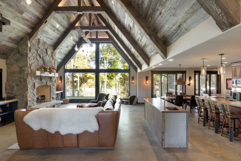 Weathered antique reclaimed wood box beams used as ceiling rafters and trusses in a modern lodge style living room and kitchen area.