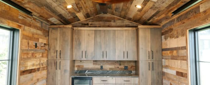 Reclaimed wood paneling covering the walls and floors of this small outbuilding. The shed has a full wall of custom cabinets as well as a beverage fridge.