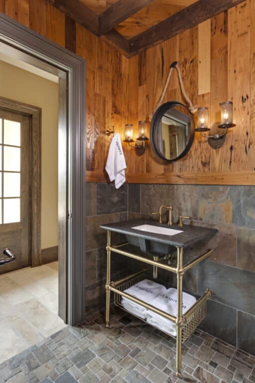 Bathroom sink against wall in half stone tile and half reclaimed wormy chestnut paneling.