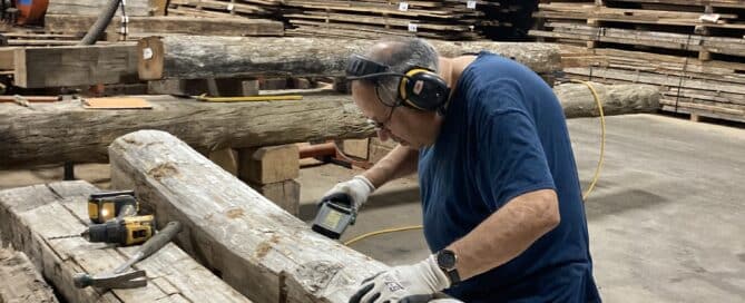 Woodworker using tools to remove nails from reclaimed timber in a commercial woodshop.