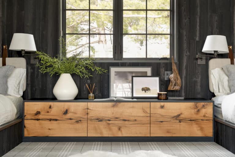 Twin bedroom with Shou Sugi Ban paneling wall between beds and behind a natural wood cabinet.