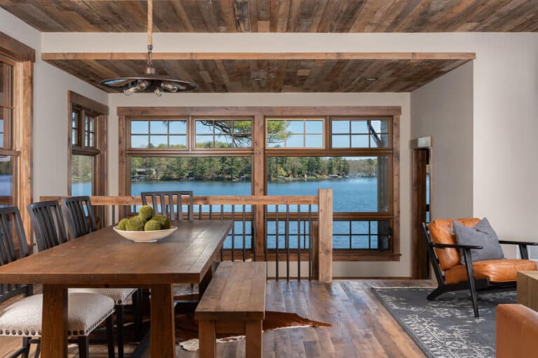 Dining table on skip oak flooring looking out large windows onto lake.