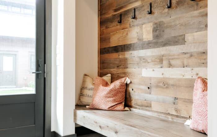 Mud room with weathered antique paneling on wall with bench and coat hooks