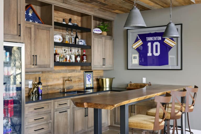 Custom home bar with reclaimed wood paneling backsplash, beverage fridge, and live edge bar countertop.