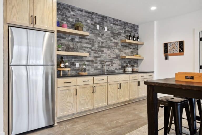 Custom home bar with sink, fridge, subway tile backsplash and sideboard counter.