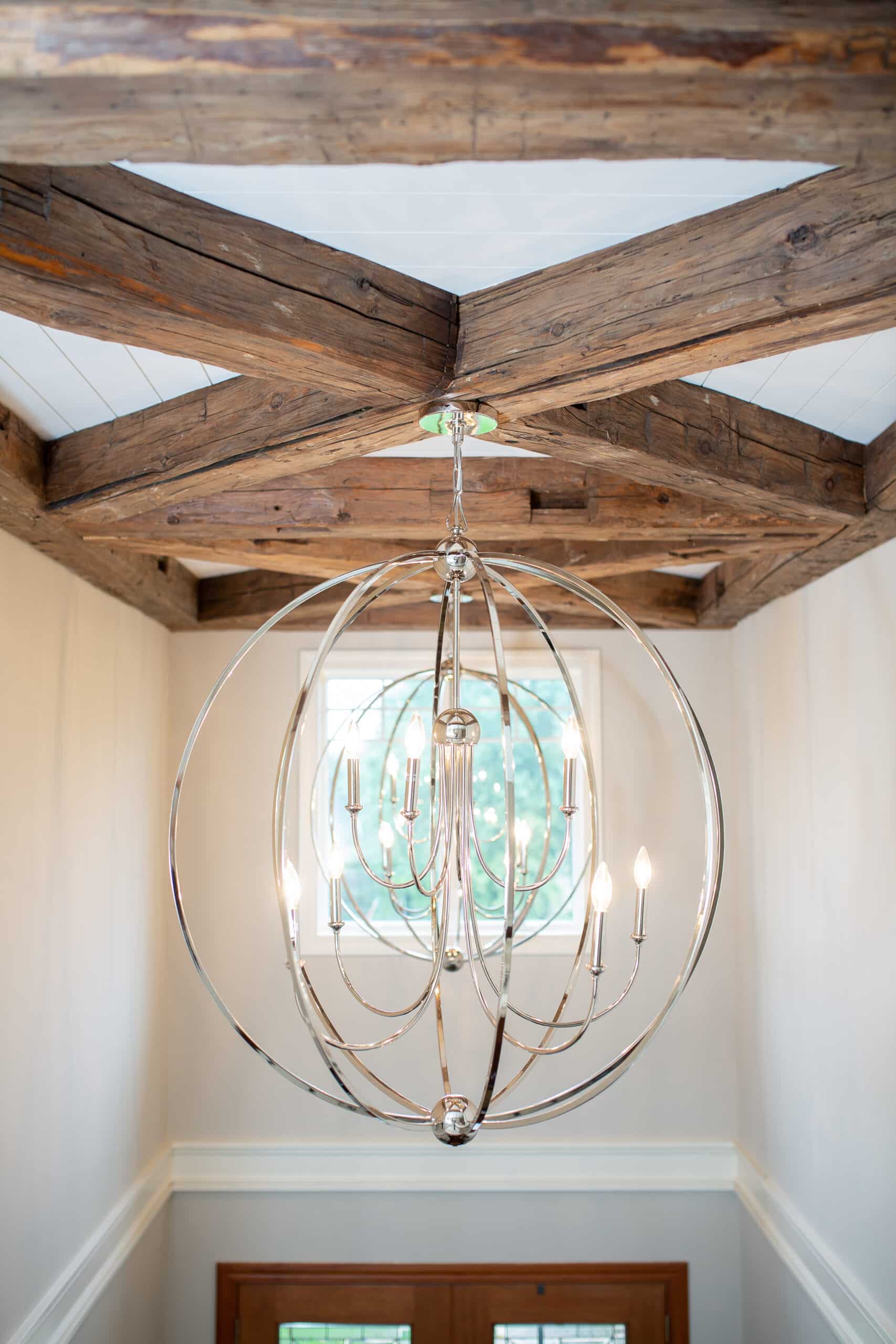 Modern, wire frame light fixture hanging from reclaimed timber coffered ceiling design