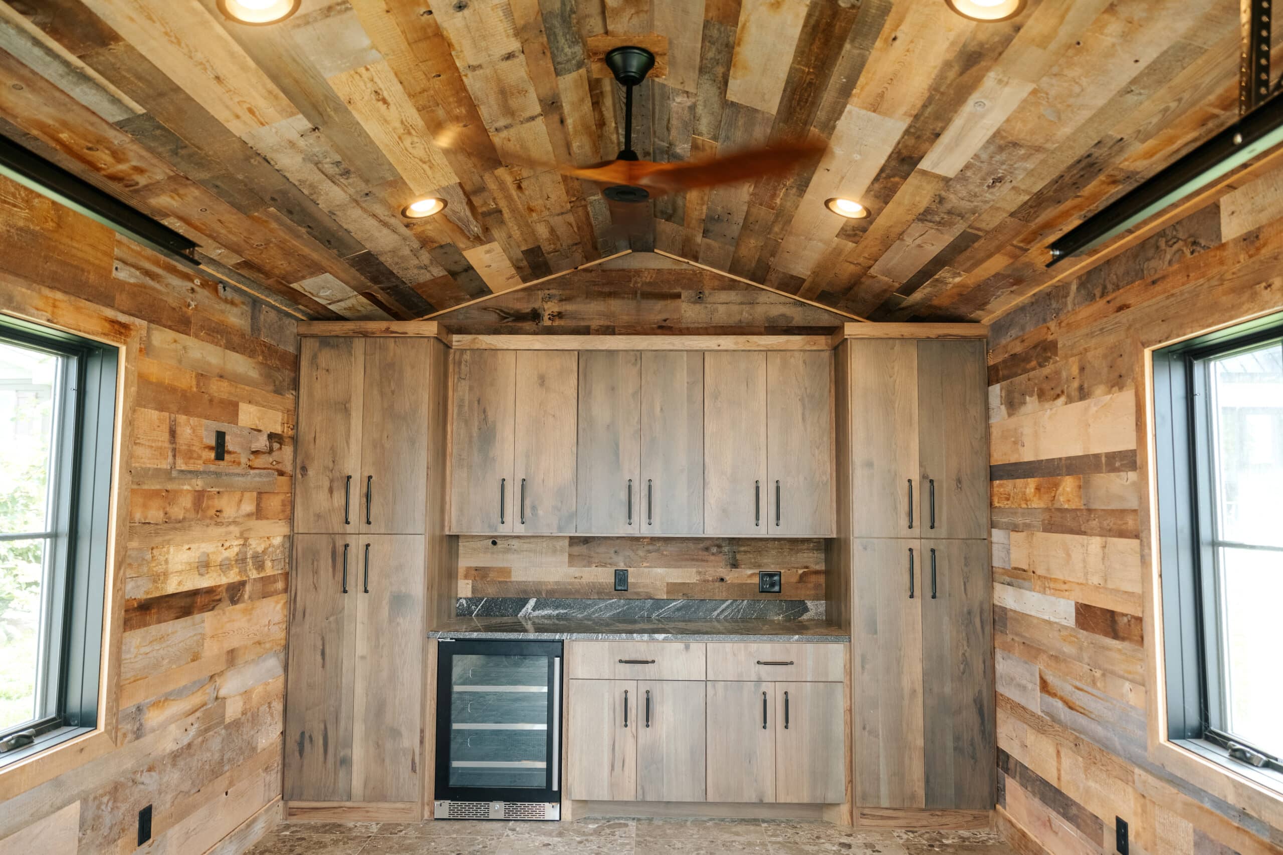 Weathered antique patina panels on walls and ceiling of custom shed with cabinets and counter