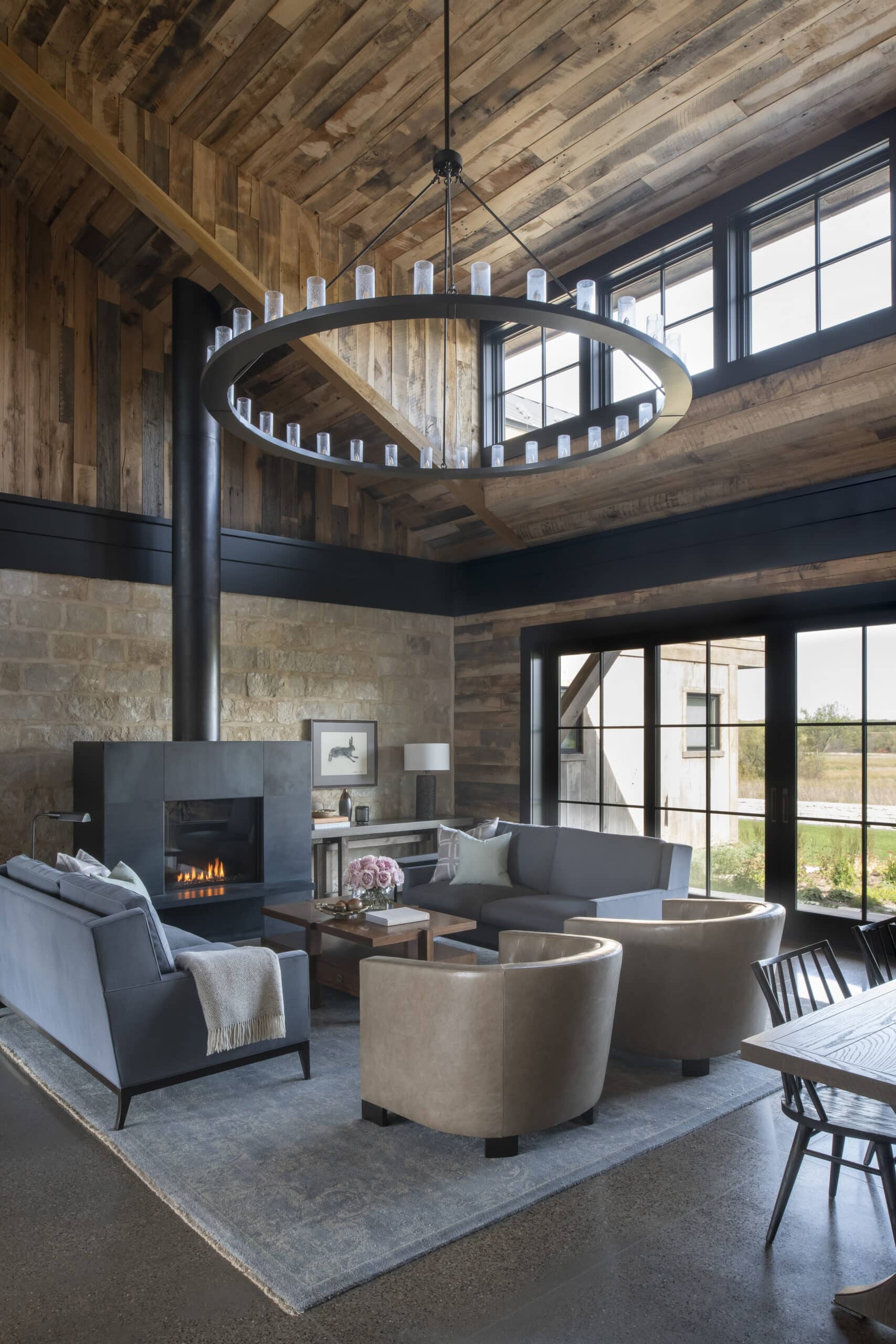 Modern living room with reclaimed wood panel ceiling, metal fireplace, and floor to ceiling windows.