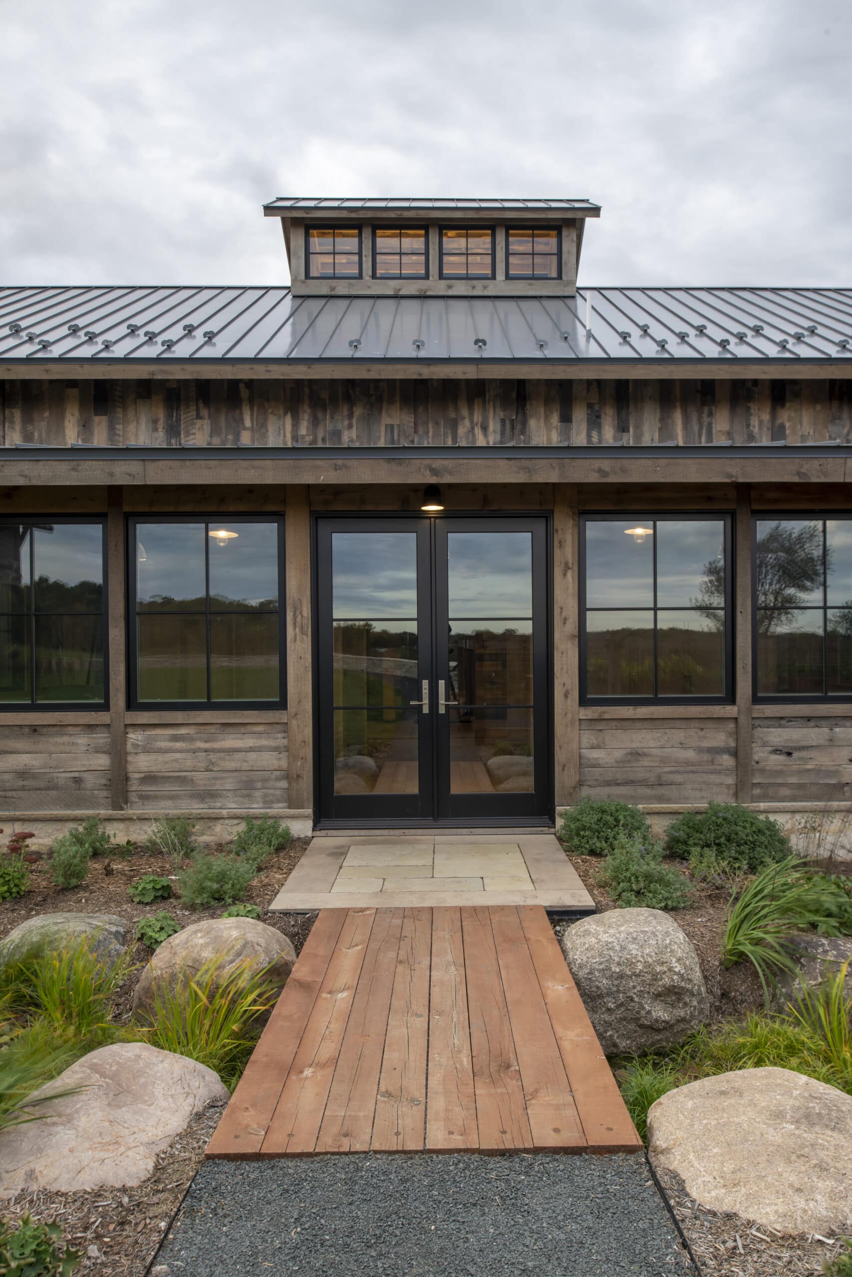 French door entry to modern vernacular home with reclaimed exterior wood siding and standing seam metal roof