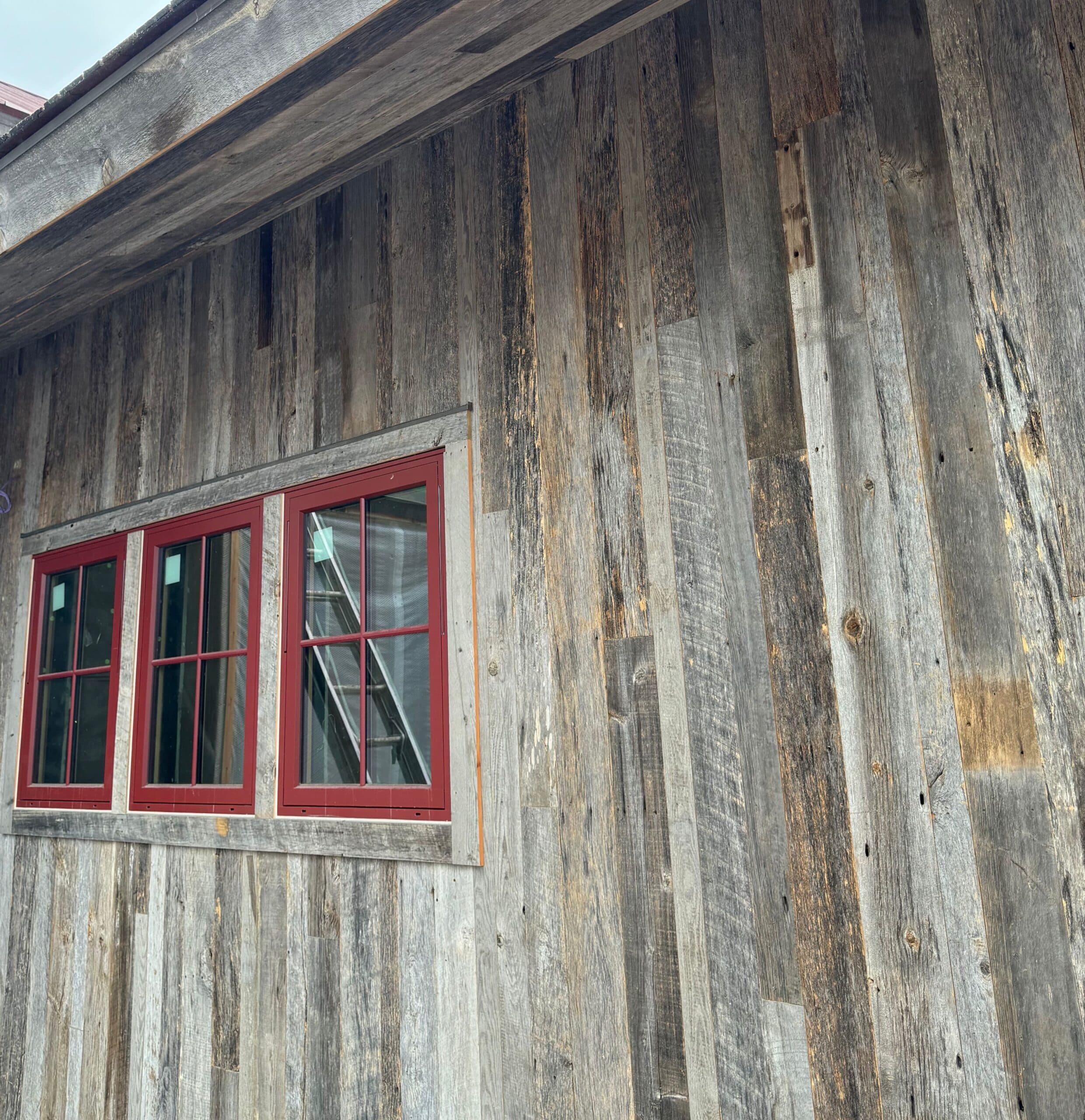 Weathered Gray reclaimed wood siding close up with red framed windows.