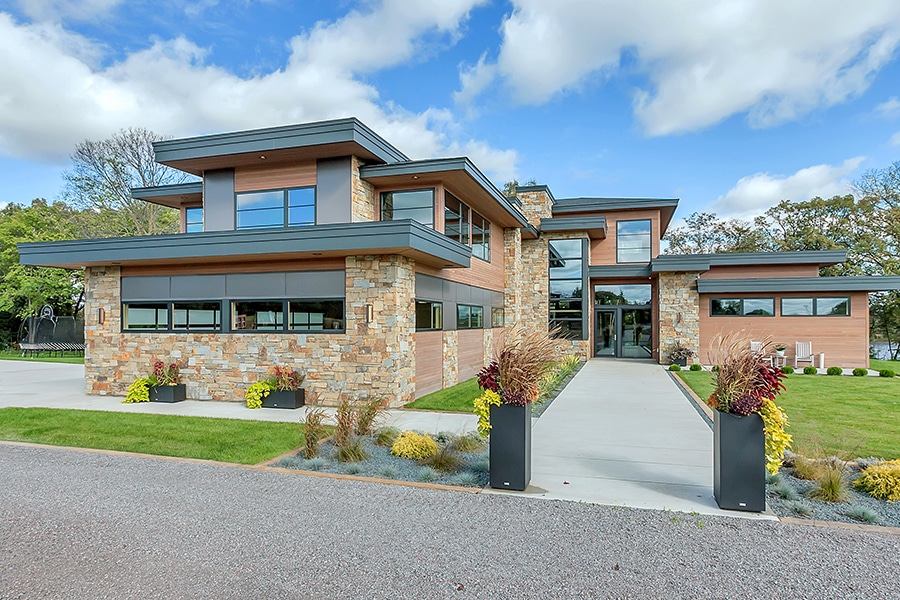 Modern home with flat roof, stone and glass exterior, and modern landscaping.