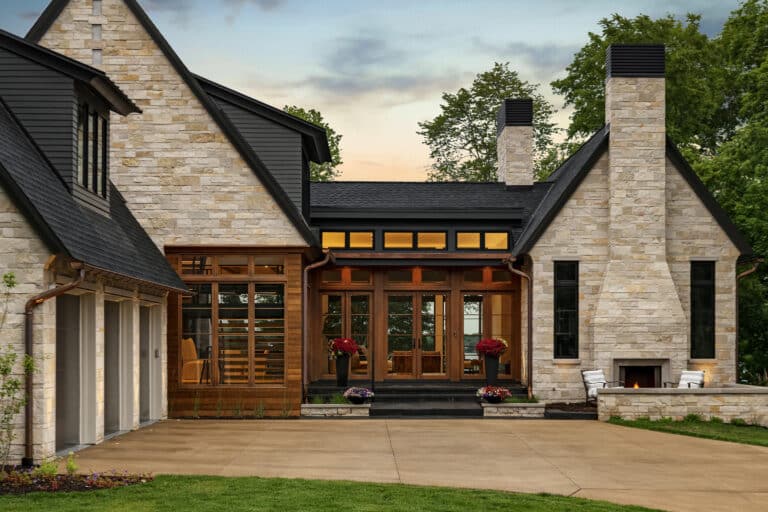 Entrance to custom luxury home with natural wood doors and windows and stone siding