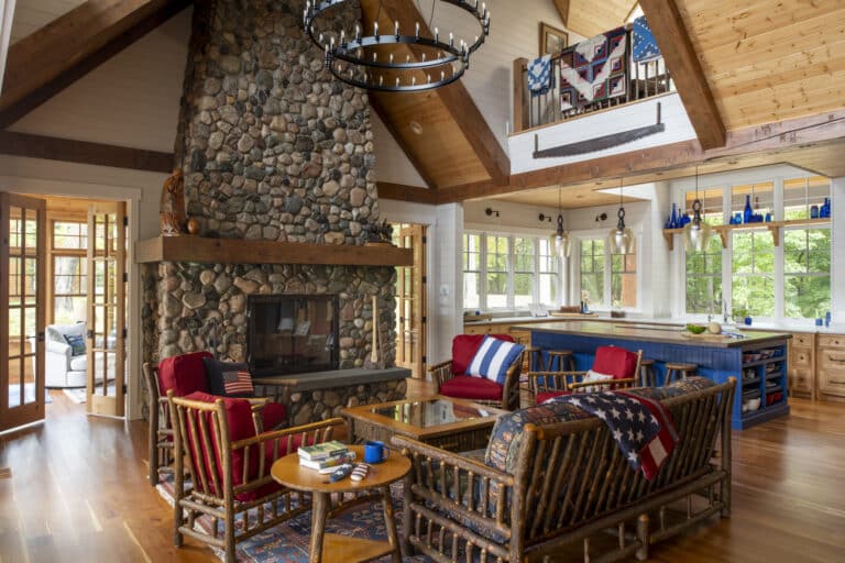 Rustic living area in lake cottage with large stone fireplace and wood furniture.