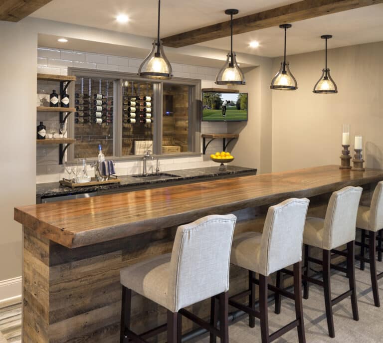 Home bar with ceiling box beams and viewing window into custom wine cellar with weathered antique panel wall