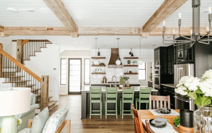 Open kitchen area with reclaimed wood ceiling beams, newels, and handrails on stairs.