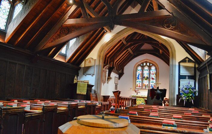 Interior of an ancient building, showing a beautifully preserved wooden church with intricate wood craft in the ceiling beams and pews, stained glass windows above the altar, and detailed carvings that highlight traditional wood crafts often found in some of the oldest structures in the world.