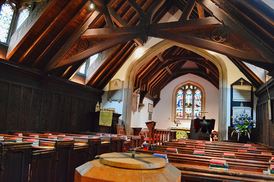 Interior of an ancient building, showing a beautifully preserved wooden church with intricate wood craft in the ceiling beams and pews, stained glass windows above the altar, and detailed carvings that highlight traditional wood crafts often found in some of the oldest structures in the world.