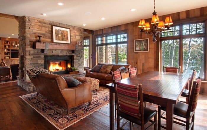 Reclaimed Douglas fir wood mantel and wall paneling add warmth and style to a rustic living room with a stone fireplace and hardwood flooring.