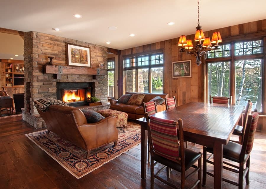 Reclaimed Douglas fir wood mantel and wall paneling add warmth and style to a rustic living room with a stone fireplace and hardwood flooring.