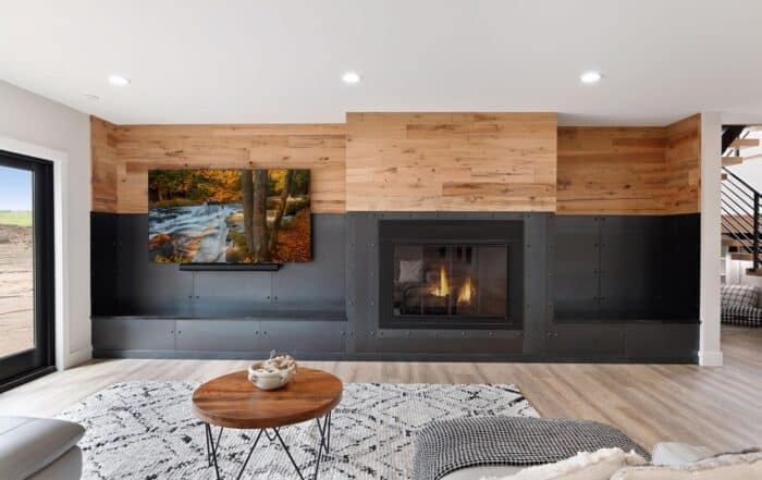 Contemporary living room showcasing reclaimed wood paneling above a sleek black fireplace, combining industrial and natural elements