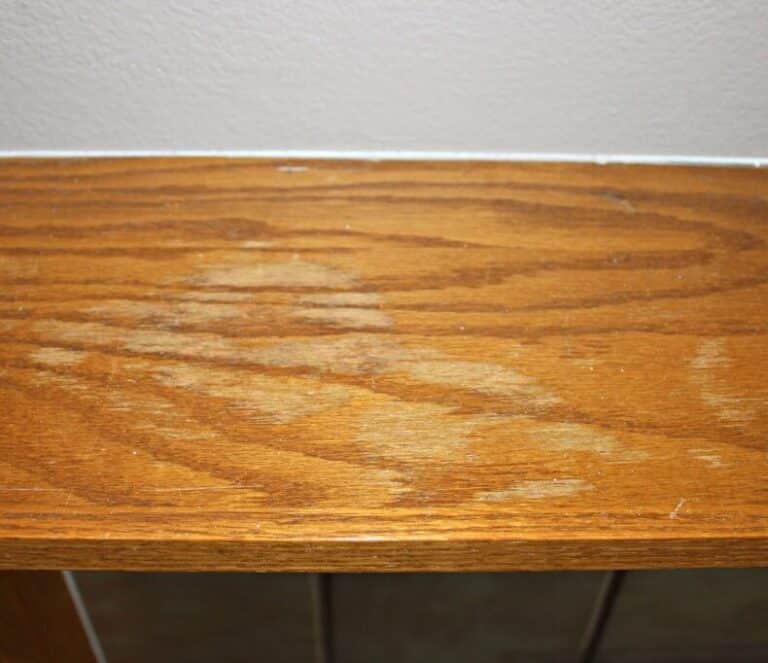 Close-up of a wood shelf with uneven staining and water damage, a common reason to remove stain from wood before refinishing.