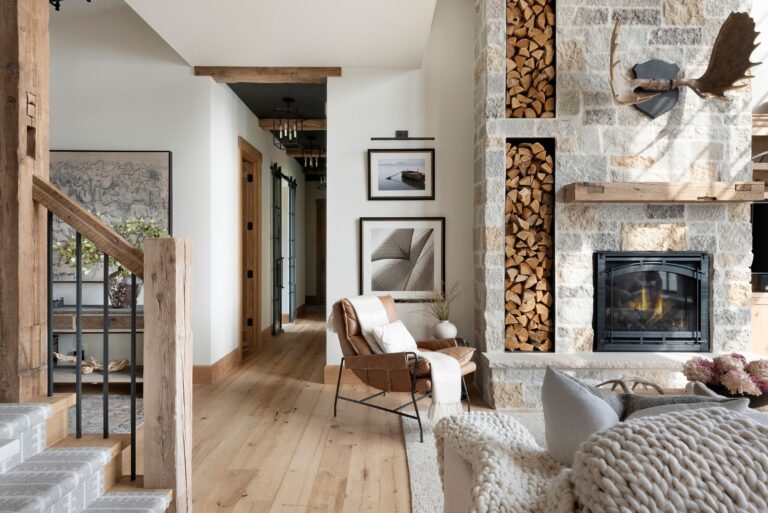Light-toned reclaimed wood floors paired with a stone fireplace and timber accents, highlighting the warmth and character of the best wood flooring.